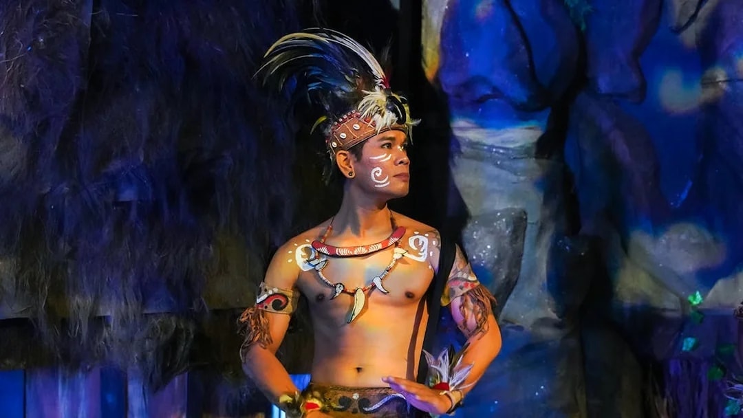 Performer in traditional attire playing drums during the Devdan Show in Bali.
