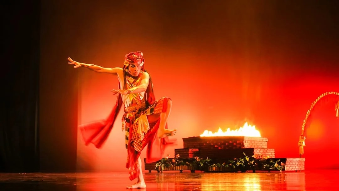 Performer in traditional costume during Devdan Show, Bali, with fire-lit stage.