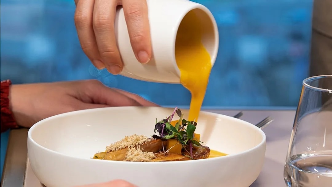 Pouring sauce over a gourmet dish at Madame Brasserie, Paris.