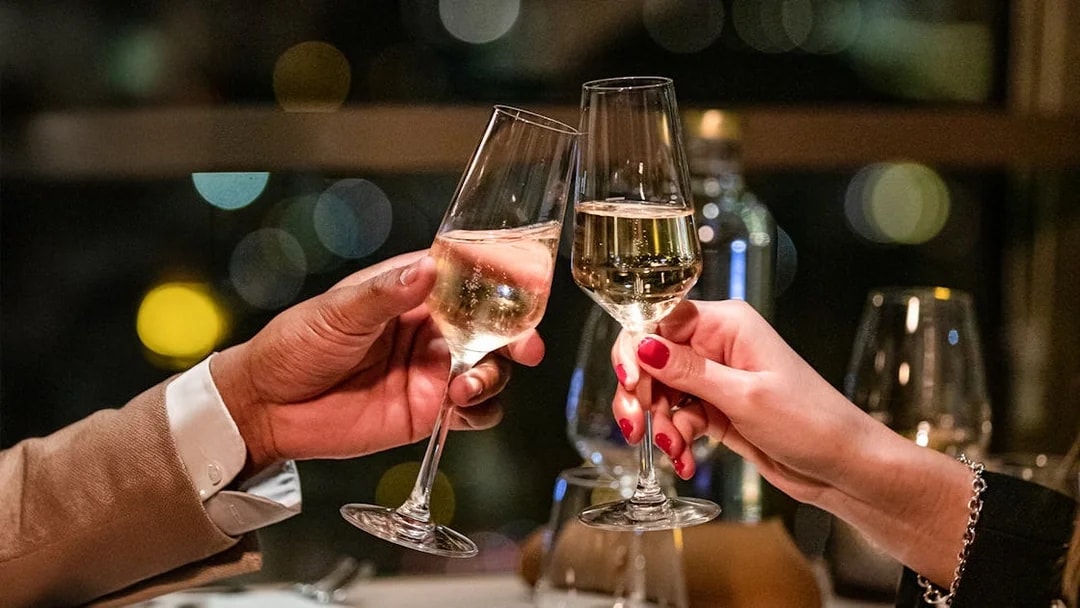 Toasting champagne glasses in a dimly lit restaurant setting.