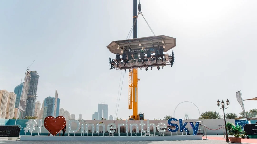 Dinner in the Sky experience suspended above Dubai with city skyline in background.
