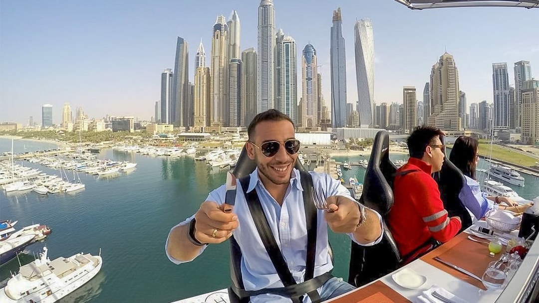 Dining experience suspended above Dubai Marina with city skyline in view.