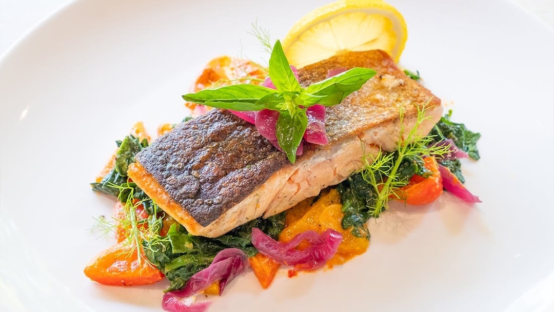 Grilled salmon with vegetables and lemon garnish served at Dinner in the Sky.