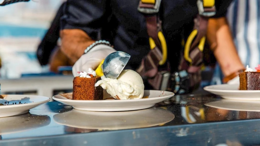 Scooping ice cream onto cake during Dinner in the Sky experience.