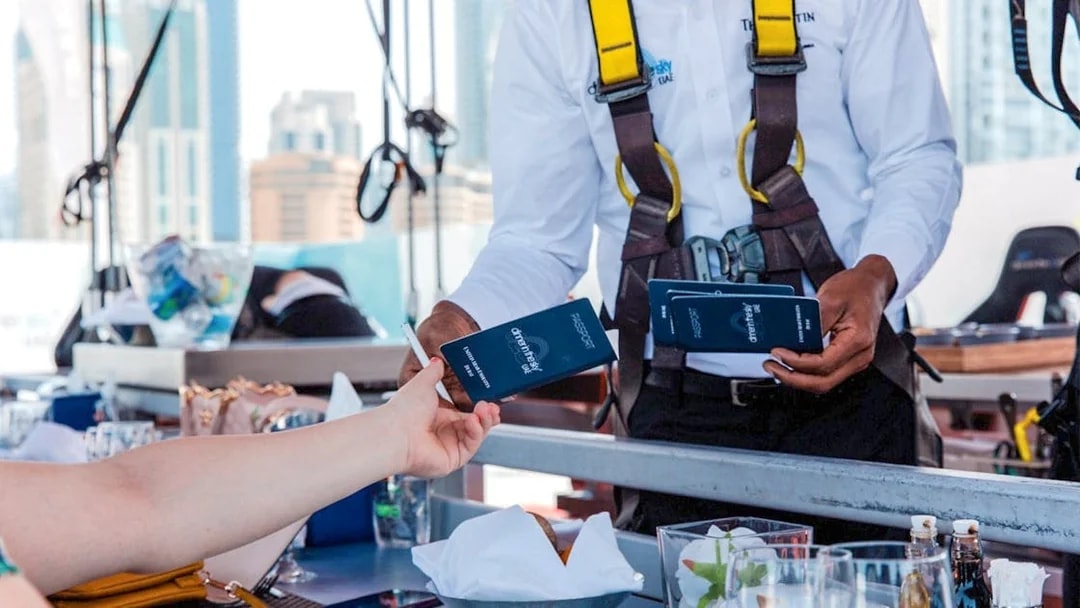 Guest receiving Dinner in the Sky tickets from staff member in harness
