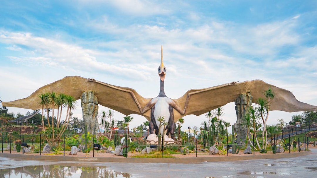 Pterosaur statue in Dino Desert park with surrounding palm trees.