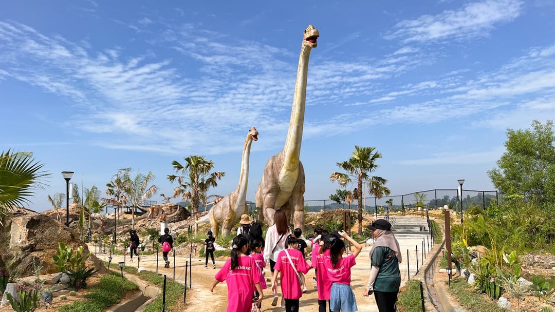Visitors walking past dinosaur sculptures in Dino Desert attraction.