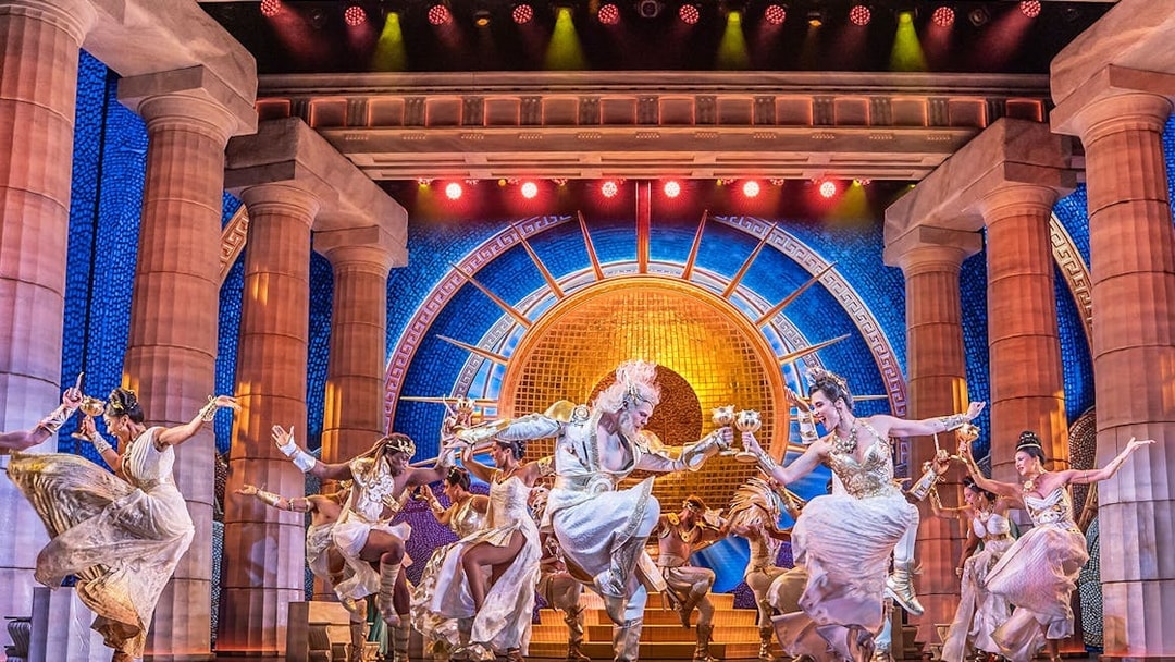 Performers dancing in a vibrant scene from Disney's Hercules stage show.