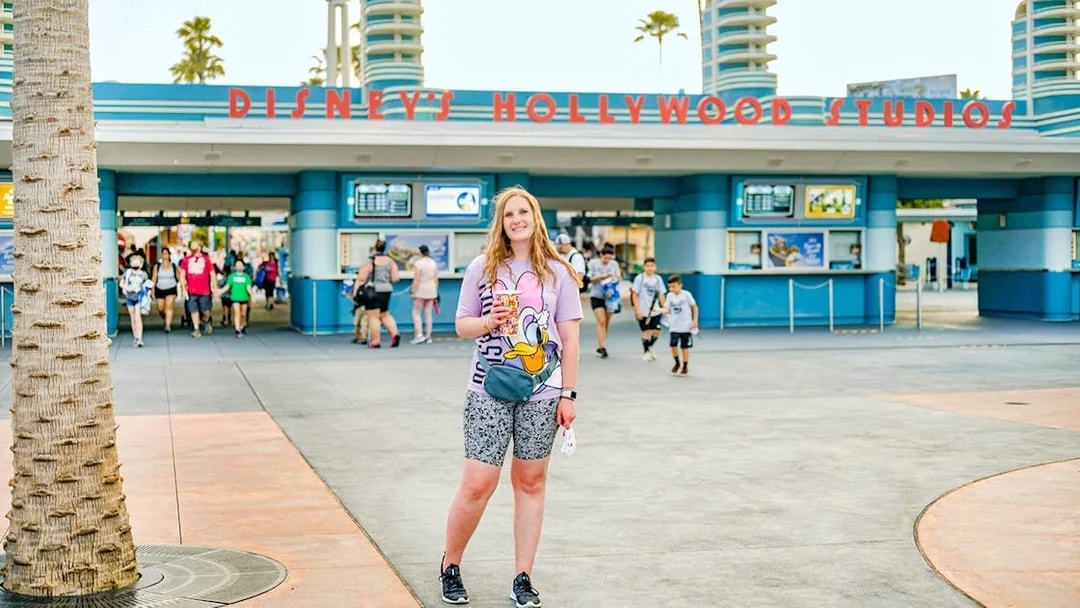 Woman standing in front of Disney Hollywood Studios entrance, Walt Disney World Resort, Orlando.