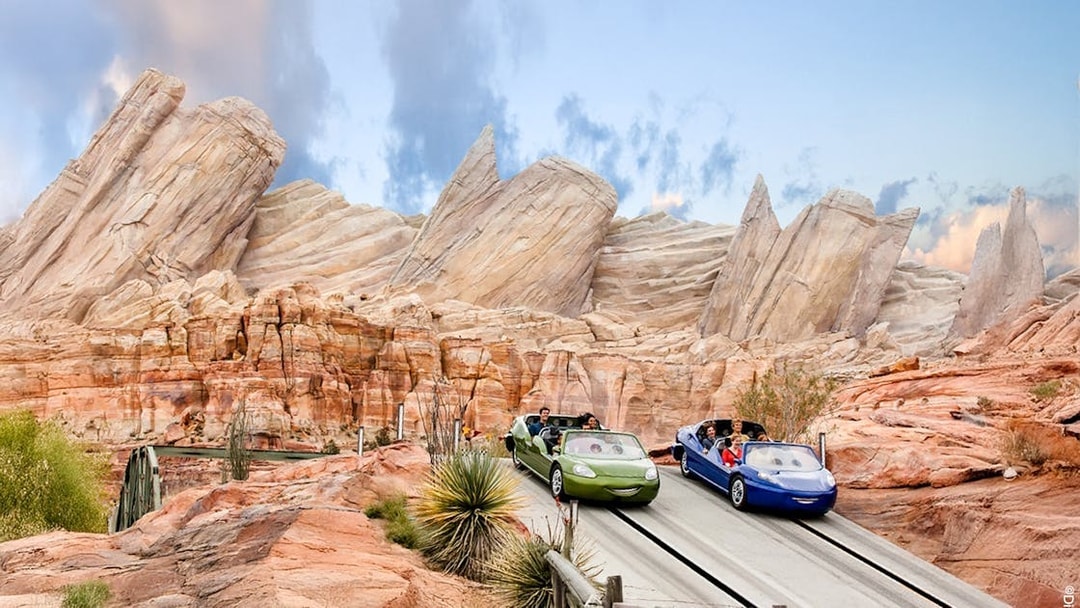 Cars on adventure track at Disneyland Adventure Park, California with rocky backdrop.