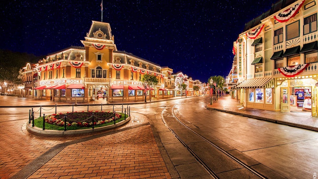 Main Street USA at night, Disneyland Park California, with illuminated shops and decorations.