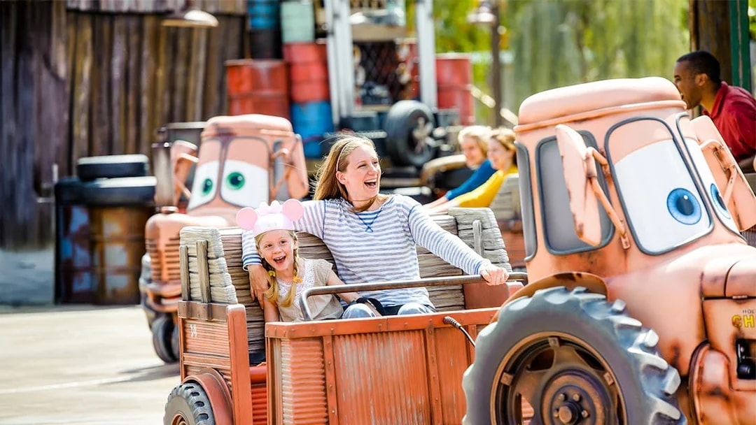 Family enjoying Mater's Junkyard Jamboree ride at Cars Land, Disneyland Adventure Park, California.