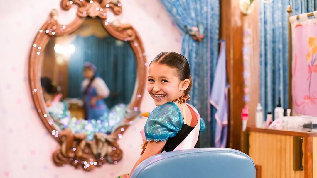 Child in costume smiling at Disneyland Park, California, with a mirror reflection.