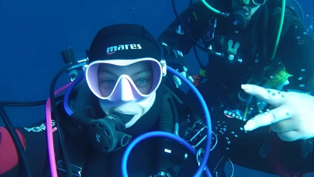 Certified divers exploring underwater in Aci Castello.
