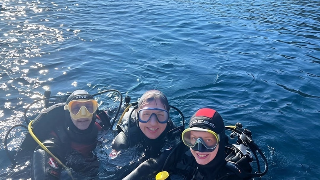 Scuba divers in the waters of Aci Castello, Italy.