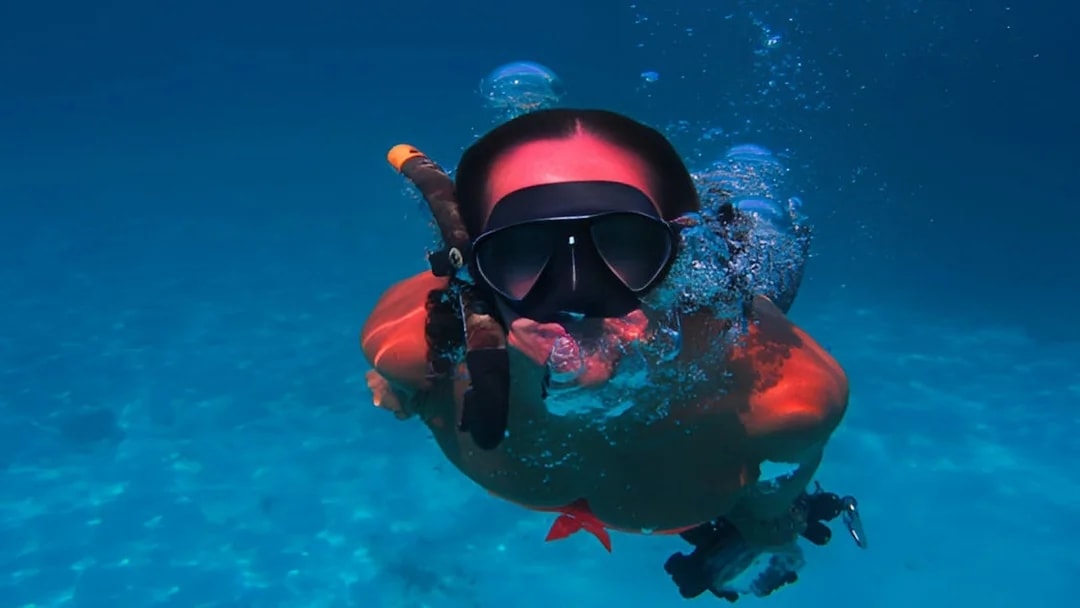 Scuba diver exploring underwater in Aci Castello, Italy.