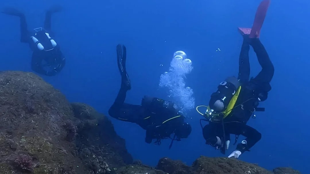 Certified divers exploring underwater rocks in Aci Castello.