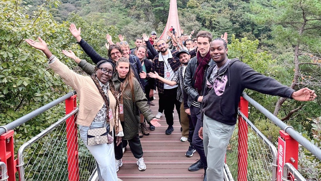 Tour group waving on a suspension bridge over a forested valley during DMZ tour.