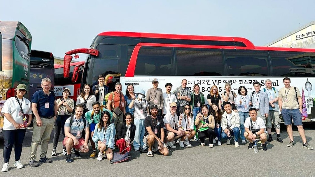 Tour group posing in front of a red and black bus on a DMZ tour in South Korea.