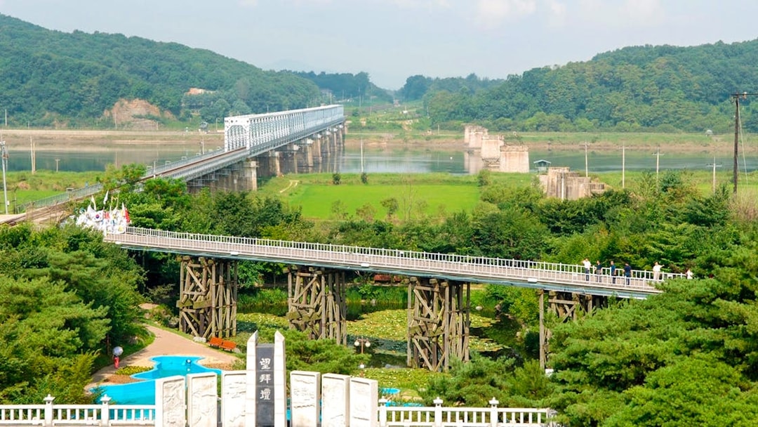 Freedom Bridge with Mangbaedan Altar in the foreground, surrounded by greenery.