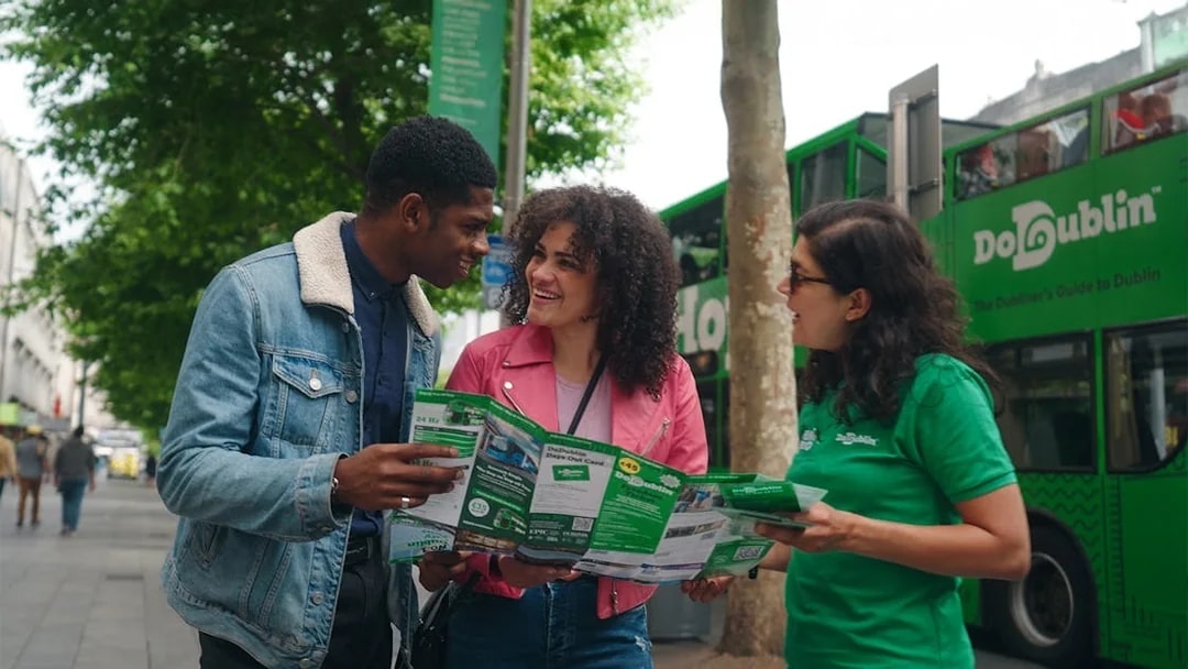 Friends using a map for a hop-on hop-off bus tour in Dublin.