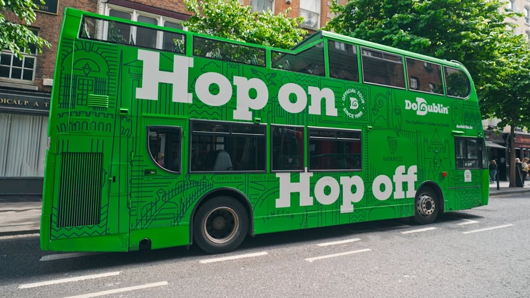 Dublin green hop-on hop-off tour bus on city street.