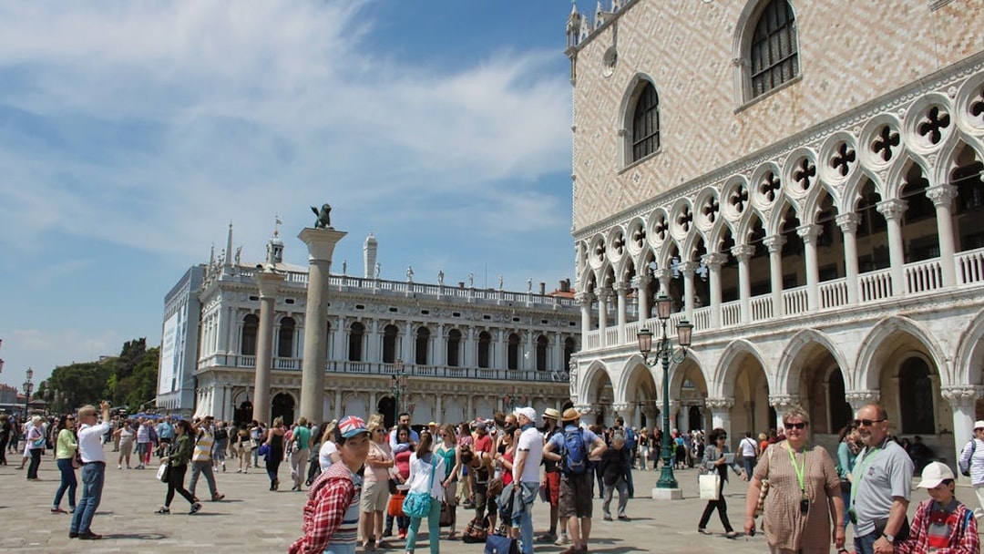Crowd outside Doge's Palace in Venice with guidebooks, near St. Mark's Square.