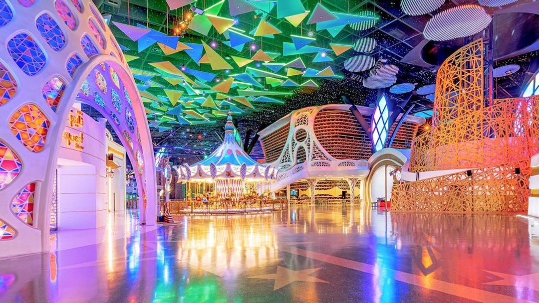 Doha Quest Theme Park interior with colorful carousel and geometric ceiling.