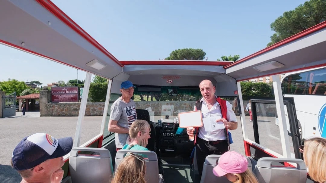 Tour guide speaking to visitors on a bus at Catacombs of Domitilla, Rome.