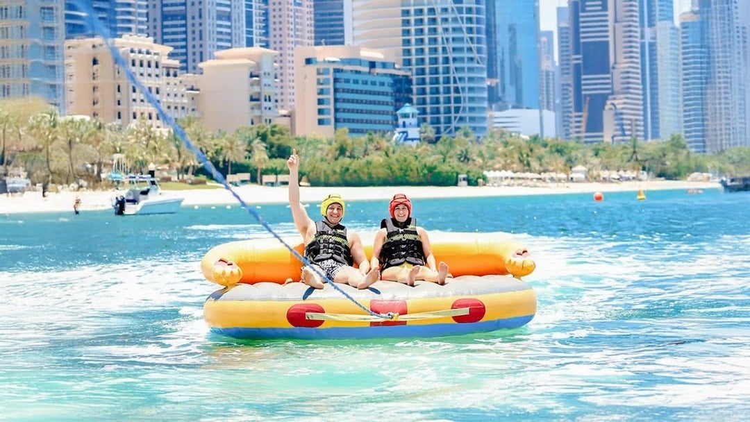 Men on a donut ride in Dubai with city skyline in the background.