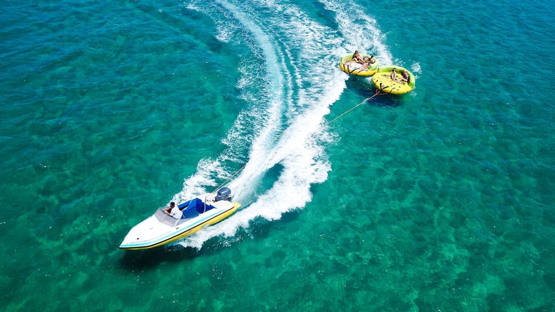 Aerial view of a speedboat towing a donut ride on turquoise waters in Dubai.