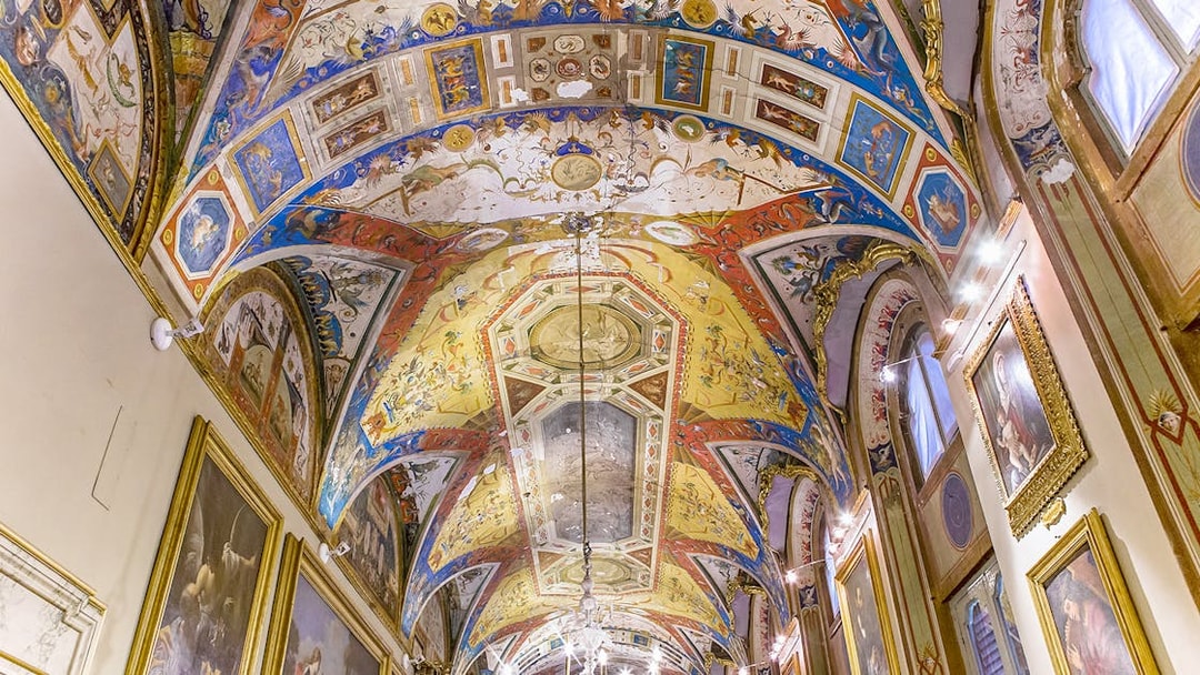 Doria Pamphilj Gallery ornate ceiling with vibrant frescoes and framed paintings.