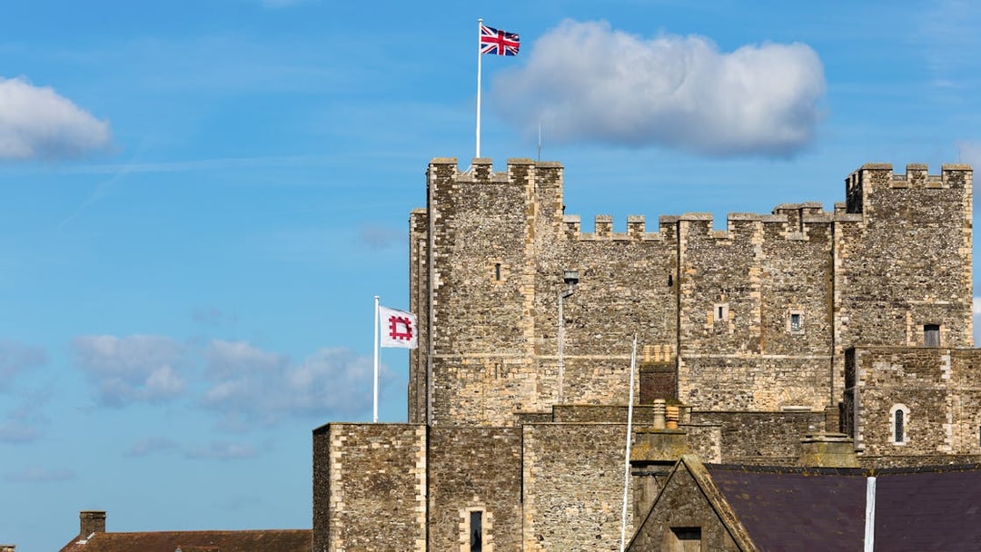 Dover Castle with Union Jack flag on a sunny day, part of Canterbury and Dover tour.