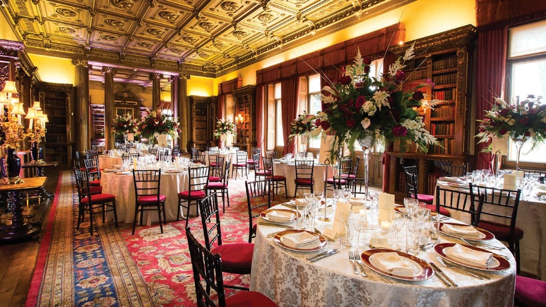 Elegant dining room setup at Downton Abbey with ornate ceiling and floral centerpieces.