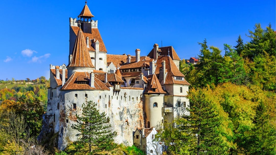 Bran Castle in Transylvania surrounded by autumn trees, part of Dracula's life journey tour.