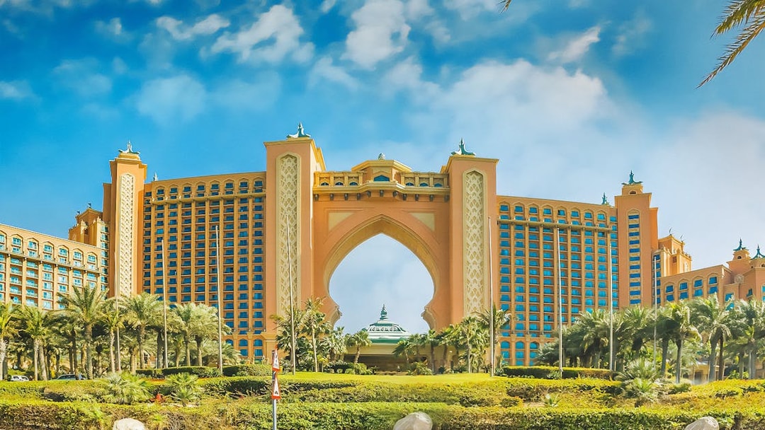 Atlantis The Palm hotel in Dubai with palm trees and blue sky.