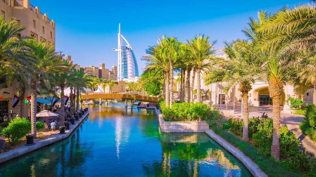 Canal view with palm trees and Burj Al Arab in Dubai.