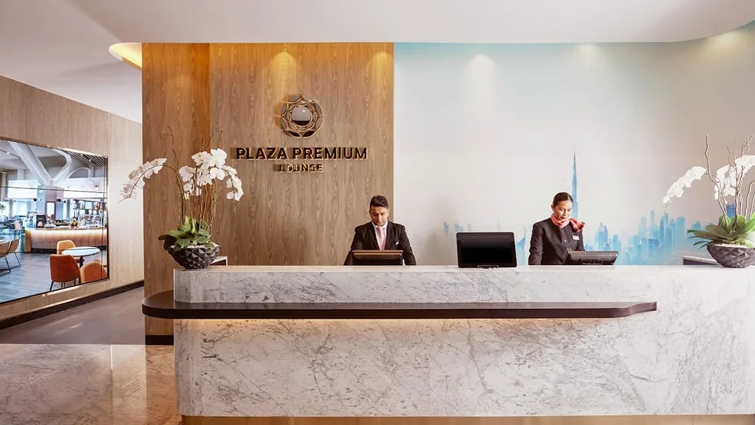 Plaza Premium Lounge reception at Dubai International Airport with staff at the desk.