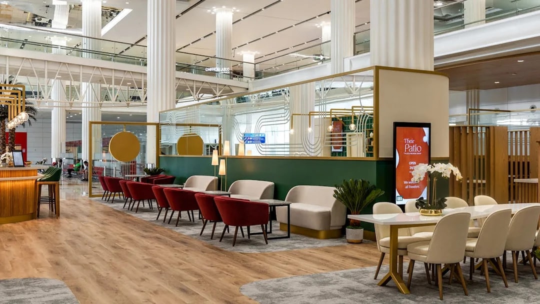 Sitting area in Their Patio Lounge at Dubai International Airport with red chairs and modern decor.
