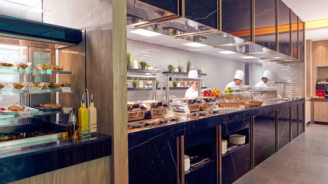 Chefs preparing dishes at a buffet in Dubai International Airport's premium lounge.
