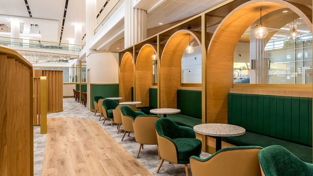 Premium lounge seating area at Dubai International Airport (DXB) with green chairs and wooden decor.