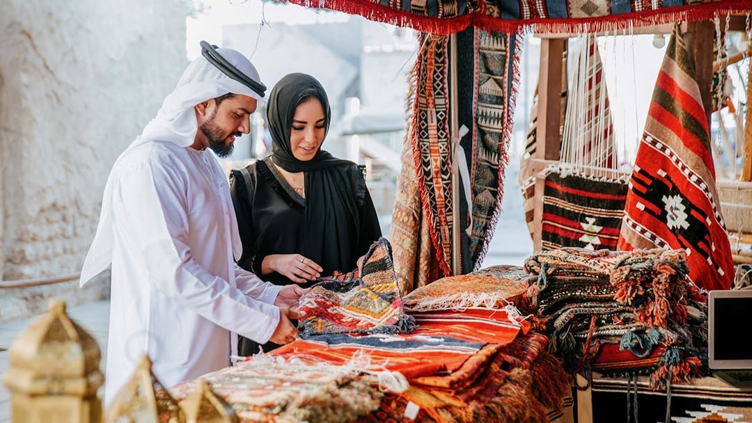 Couple browsing traditional rugs at Heritage Village market, Dubai.