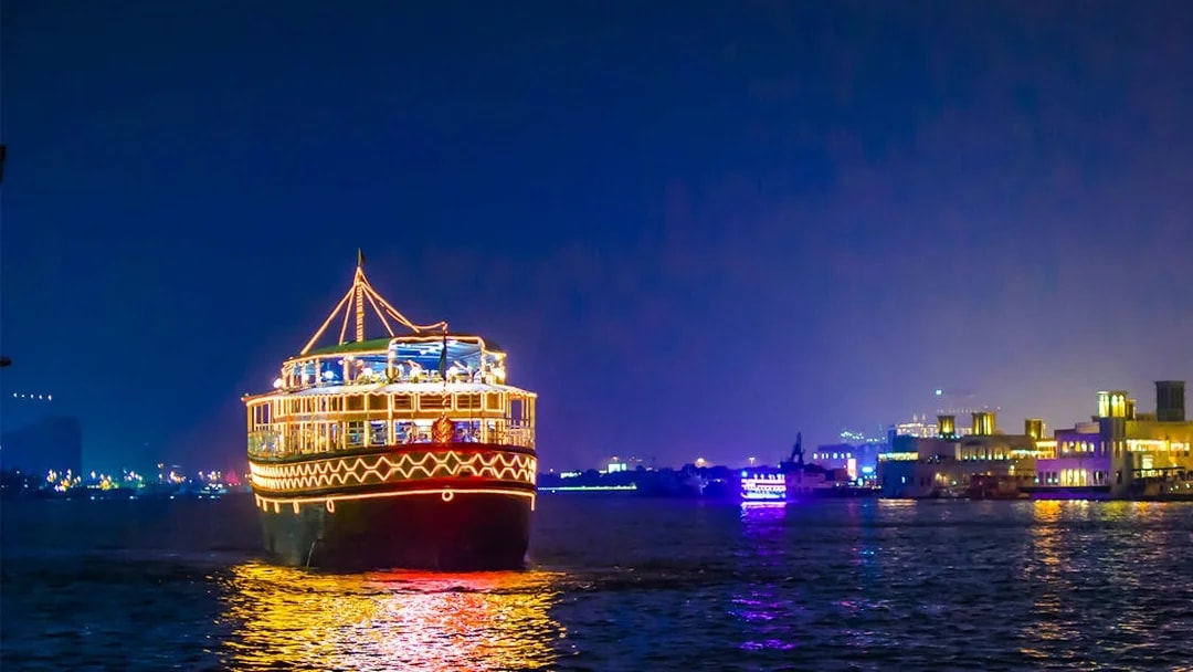 Dhow cruise with lights on Dubai Creek at night.