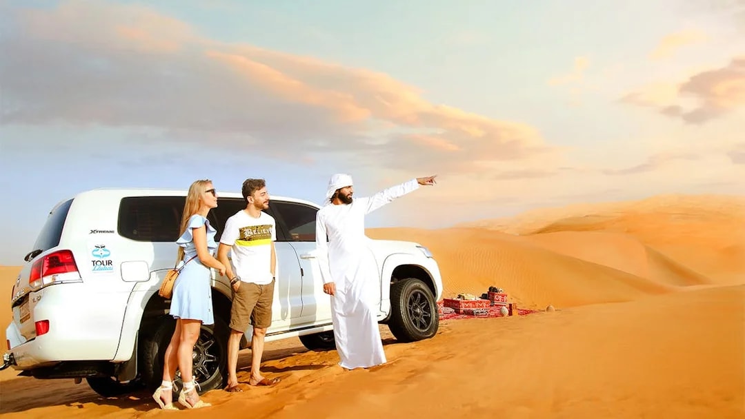 Traveller with guide beside SUV after dune bashing in desert safari.