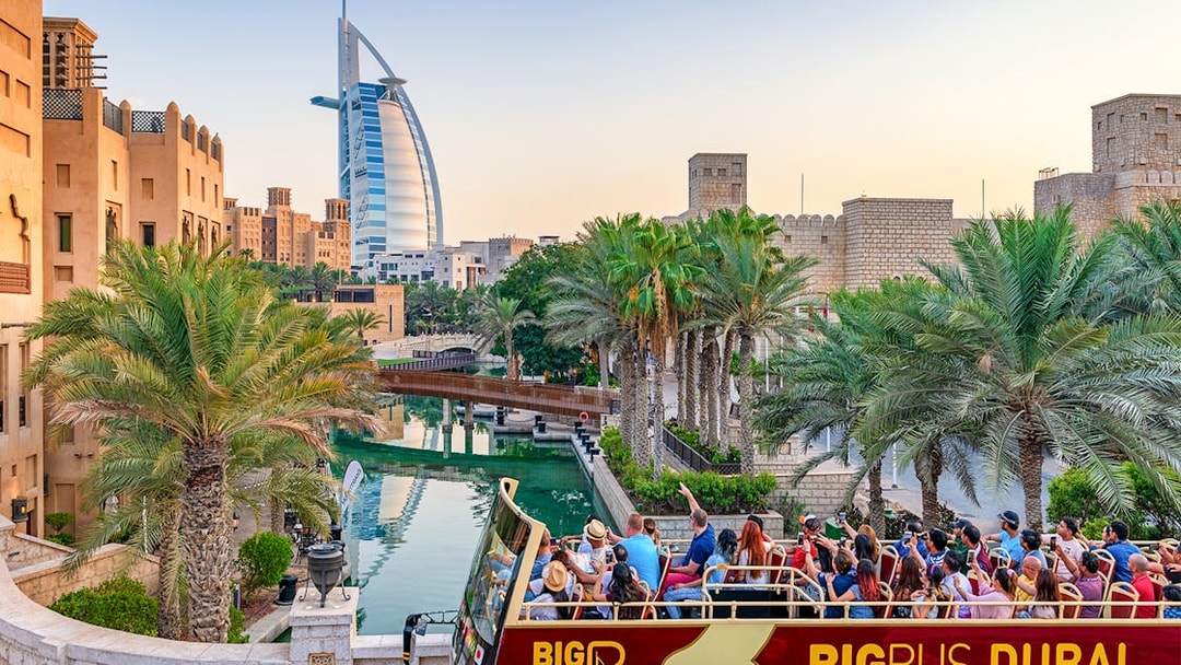 Dubai cityscape with Big Bus tour and Dhow Creek cruise in foreground.