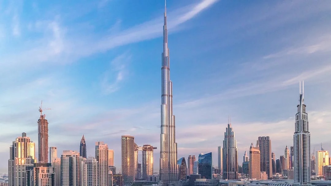 Burj Khalifa towering over Dubai skyline at sunset.