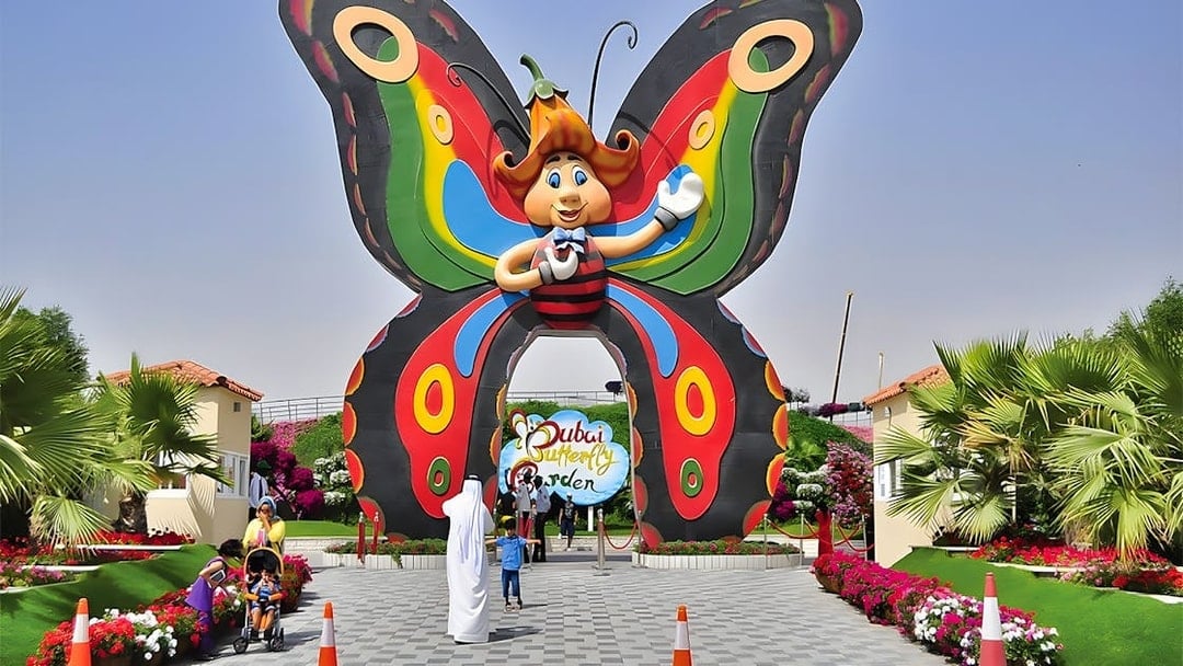 Entrance to Dubai Butterfly Garden with colorful butterfly arch and visitors.