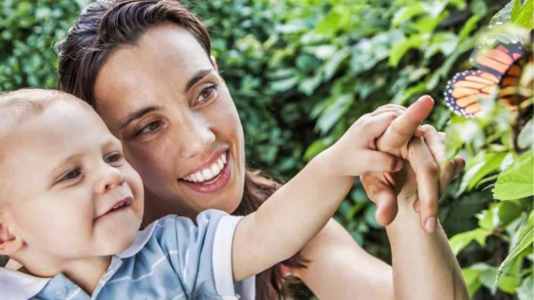Mother and son observing a butterfly at Dubai Butterfly Garden.