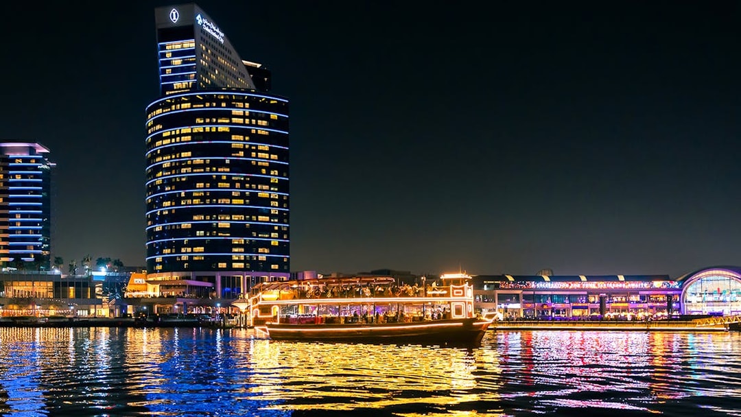 Dubai cruise boat illuminated on Dubai Water Canal at night.