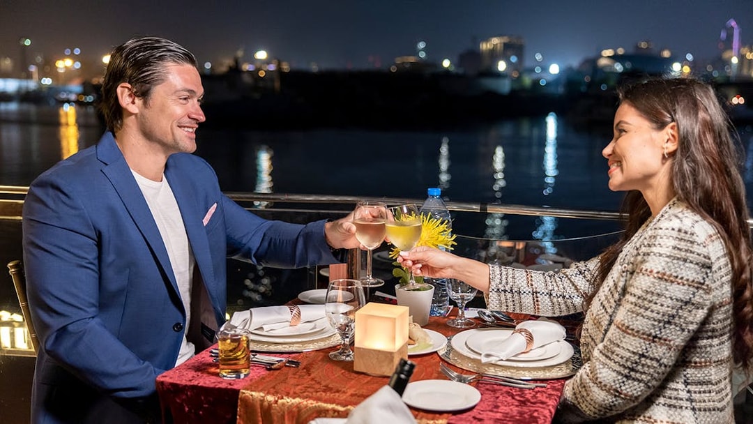 Couple toasting wine glasses on Luxury Dhow Cruise at night.